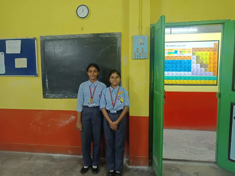 Zwei Schülerinnen in Uniform vor einem Klassenzimmer