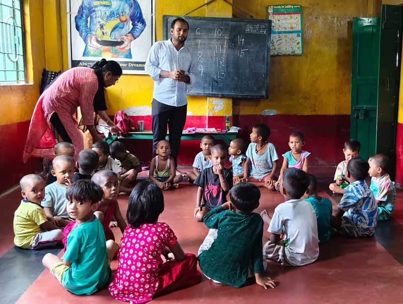 Kinder sitzen in einem Klassenzimmer von KMWSC auf dem Boden